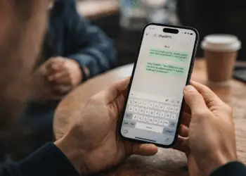 Persona usando WhatsApp en el móvil en una cafetería, ideal para explicar el Modo Restrictivo Whatsapp y proteger chats.