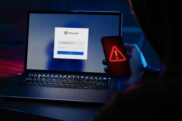 Portátil con pantalla de login de Microsoft y smartphone con icono de alerta roja, ilustrando el phishing de consentimiento en Microsoft 365.